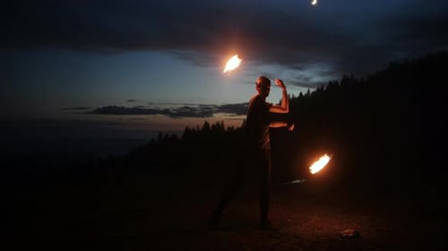 Man Fire Juggling with Flaming Torches at Night