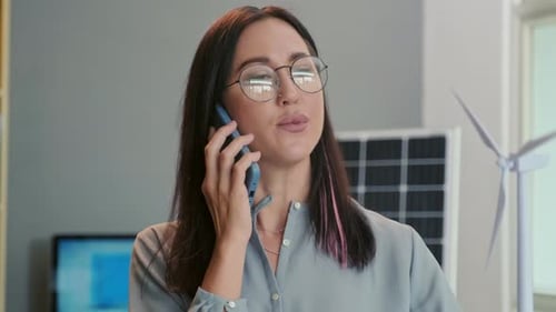 Woman Talking On Phone in Office With Wind Turbine