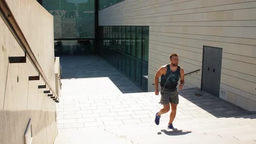 Fitness, Sport, Training and Lifestyle Concept - Young Man in Earphones Running