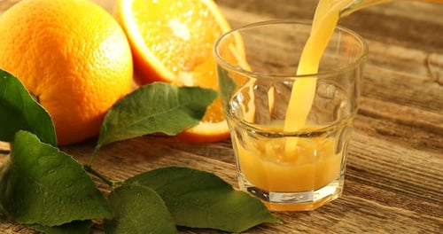 Fresh Orange Juice Being Poured on Wooden Table