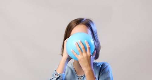 Girl Blowing up Light Blue Balloon Close Up