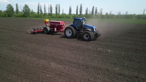 Blue Tractor working on the field planting sunflower in Ukraine