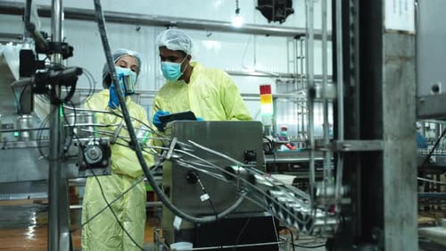 Deux ouvriers de l'industrie inspectent et contrôlent la bande transporteuse de l'usine.