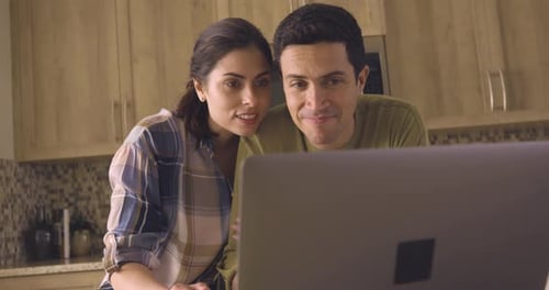 Smiling Couple Looking at Laptop in Kitchen