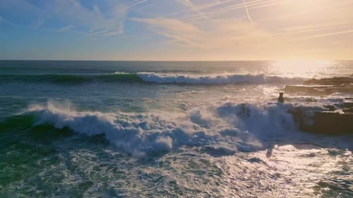 Stormy ocean waves crashing on volcanic rocks seashore at sunny day in slow motion