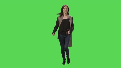 Casual brunette female in a coat is running on a mock-up green screen in the background.