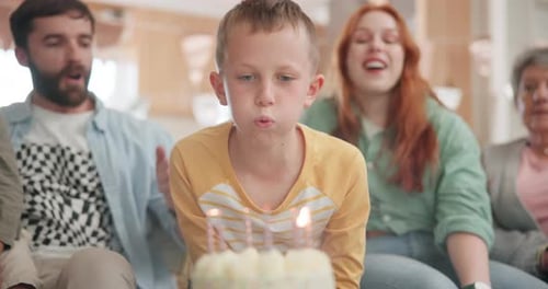 Boy Blowing Out Birthday Candles with Family