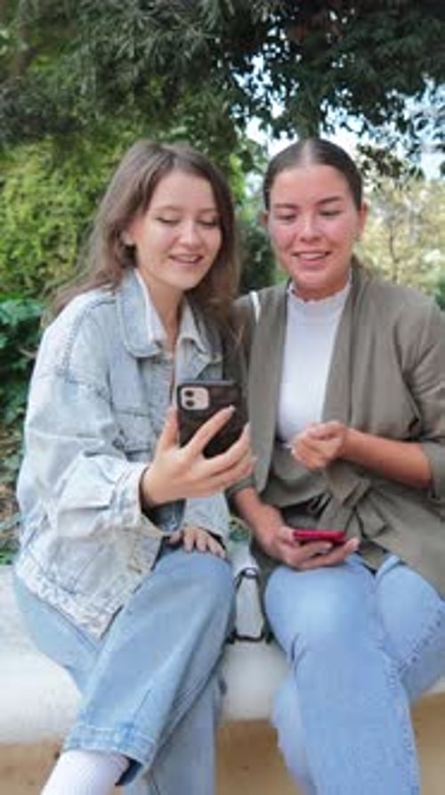 Two Women Using Phone on Park Bench