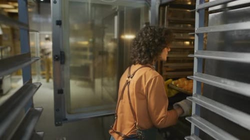 Woman Baker Pulling Tray of Croissants from Oven