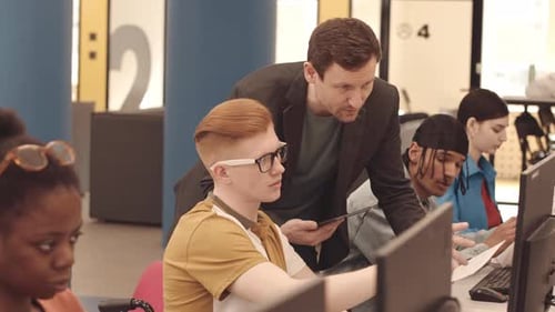 Instructor Reviewing Student's Work in Computer Lab