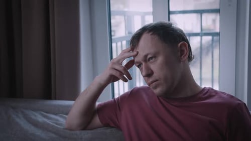 Man is Experiencing Stress His Face Serious and Upset the Man is Sitting on the Sofa