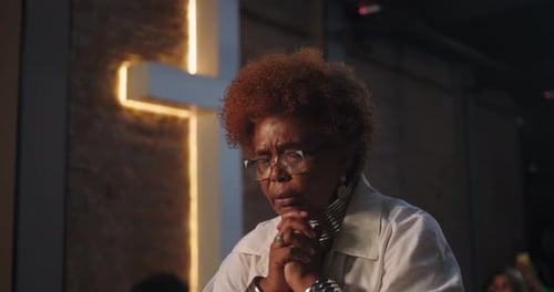 Devout Woman Praying in a Dark Church