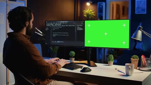Programmer Typing Complex Code on Green Screen Computer in Neon Lit Home Office