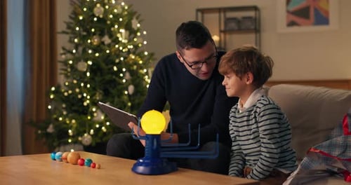 Father and Son Exploring Solar System Model at Christmas