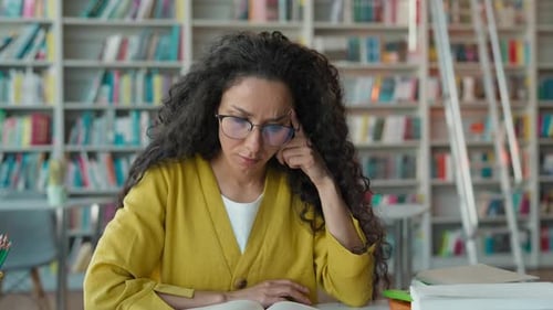Depressed Hispanic Latino Woman Holding Headache Pain Reading Textbook in Library Female Girl