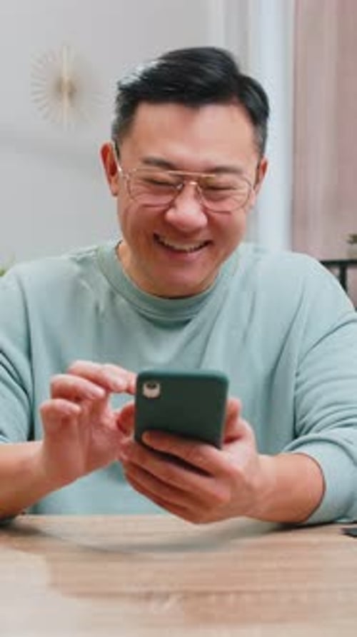 Man Using Mobile Phone at Table Indoors