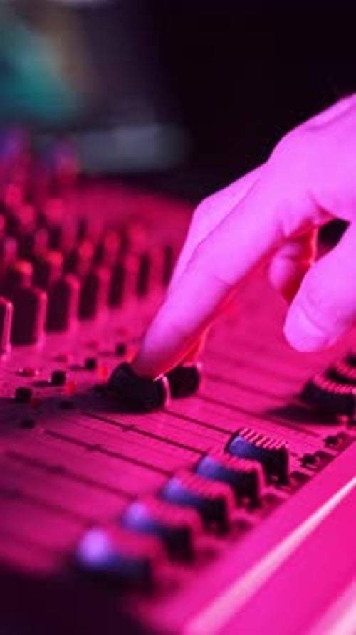 Vertical Male Hand Adjusting Faders Up And Down on Audio Mixer in Neon Light