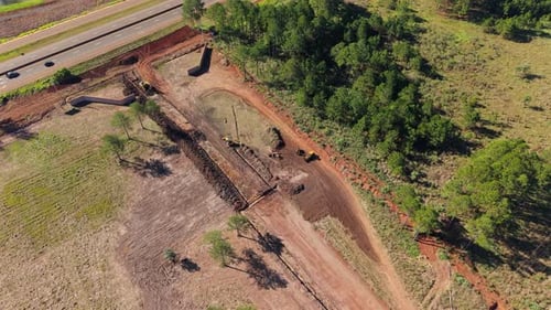 Aerial drone view of construction site with excavators clearing land near forest road
