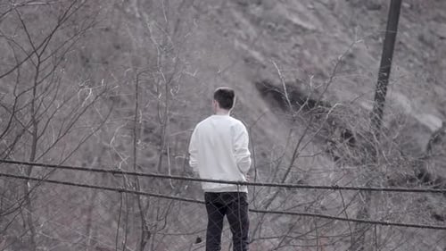 Rear view of a man standing at the edge of an autumn grey dirty slope