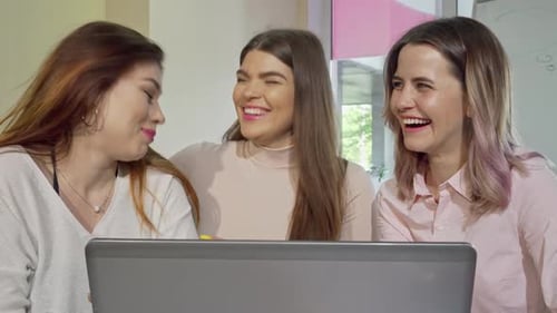 Three Joyful College Girls Sharing Laughter While Studying Together