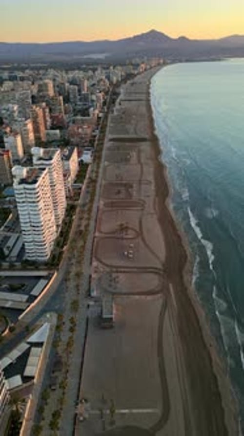 Aerial drone view of palm trees on a promenade near the beach and buildings along coastline of the c