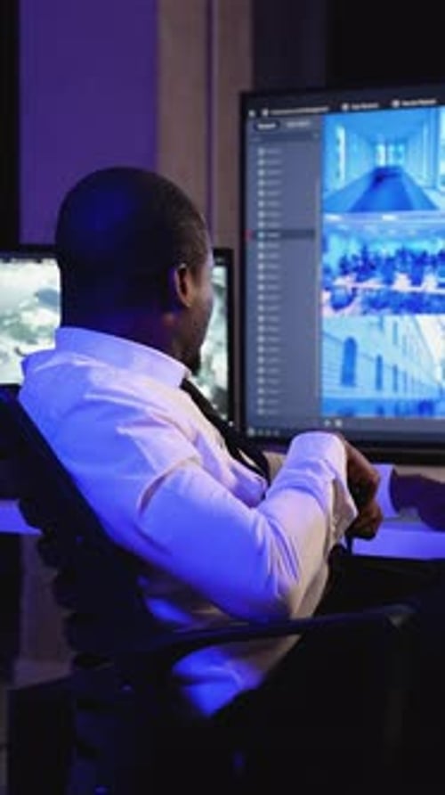 Security Guard Monitors Surveillance Footage at Night