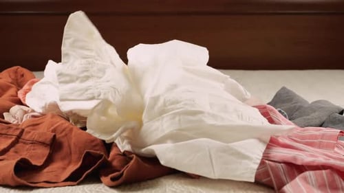 Clothes being dropped on a bed