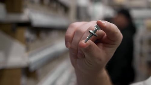 Shopper Examines Screw Bolt with Washer in Construction Store Hand Lifts Hardware Piece Amid White