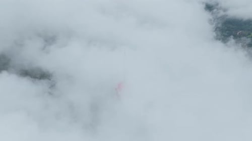 Aerial view of turyapada tower emerging from dense clouds in bali