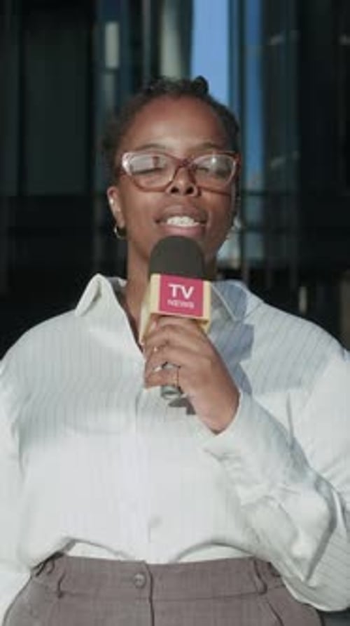 Vertical of African American Female Journalist Recording News Report in City