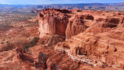 Flying closer to the huge red rocks with steep walls in the dry desert.