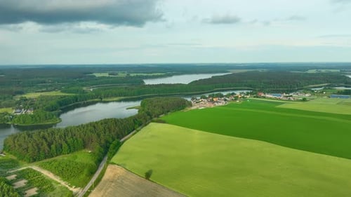 Aerial view of a rural landscape featuring lush green fields, a winding river, and a small village.