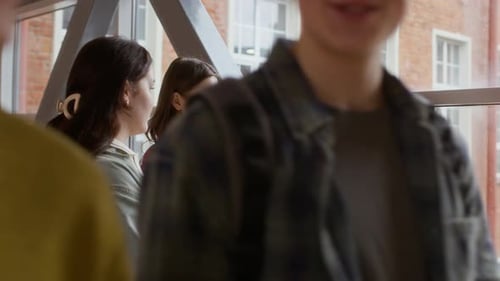 Diversas namoradas da geração Z conversando depois das aulas enquanto colegas do sexo masculino passam