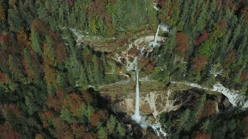 Aerial view of two big and small waterfalls in the mountains surrounded by forest in fall autumn.