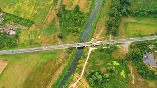 aerial drone shoot. Flying over a bridge green field in a rural landscape. Top view of trees in fore