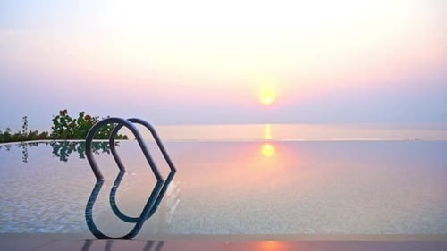 Empty Outdoor Infinity Pool with Panoramic Sea View, at Sunrise. Sun Reflecting in the Surface of th