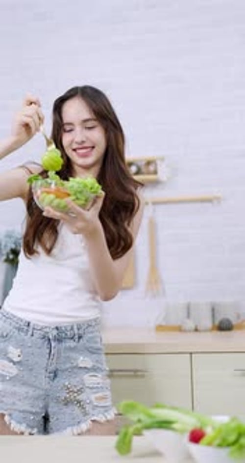 Young Woman Enjoys Fresh Green Salad in Kitchen