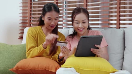 Women Using Tablet with Credit Card on Couch