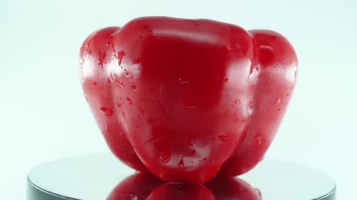 A close up shot of a sweet red wet pepper on a reflecting rotating stand 360, slow motion, 4k video
