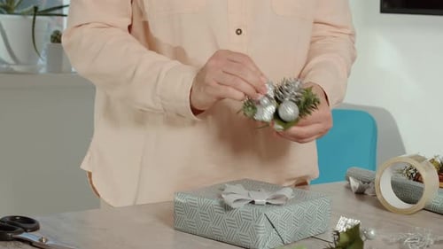 Woman Decorating a Christmas Gift with Silver Ornament