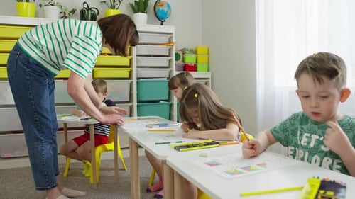 Teacher assists children in bright classroom setting