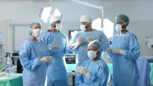 Portrait of diverse surgeons wearing surgical gowns in operating theatre, slow motion