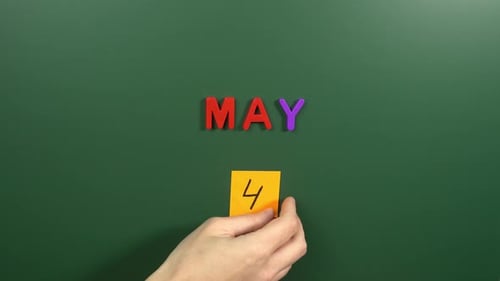 Hand sticking a sticker 4 May calendar day on school board. 4 date of May. Fourth day May. 4th