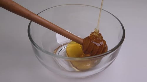 Golden Honey Pouring into Glass Bowl with Dipper