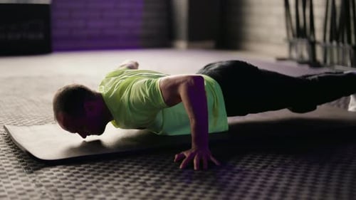 Man Doing Push Ups on Mat in Gym