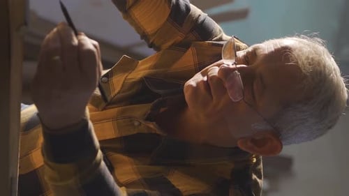 Gray-Haired Adult Craftsman Works Wood Piece