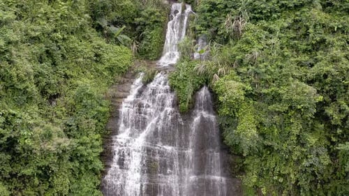 Beautiful forest waterfall cascading over rocky mountainside, 4K aerial view