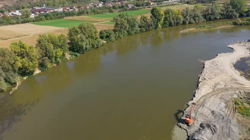 Aerial view of backhoes digging sand and gravel with shovels from the river by drone