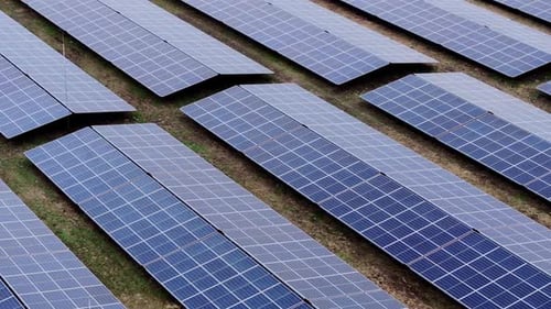 Aerial Flight Over Aligned Solar Panels In Forward Motion With Downward View
