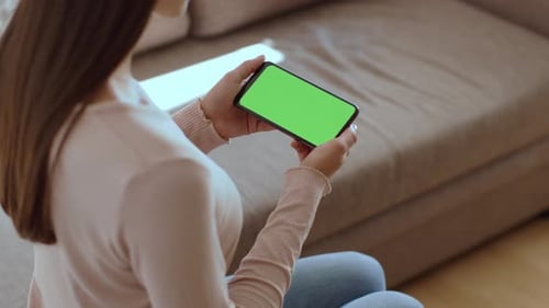 Unrecognizable Young Woman Watching Tv Online on Smartphone with Blank Green Chroma Key Screen Empty